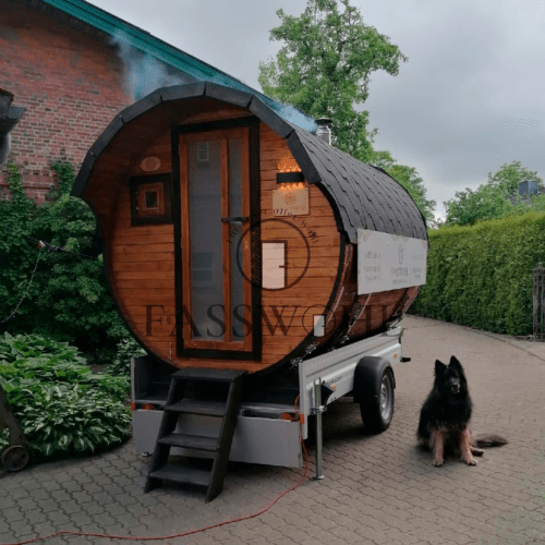 Ein Hund der neben dem Saunafass sitzt