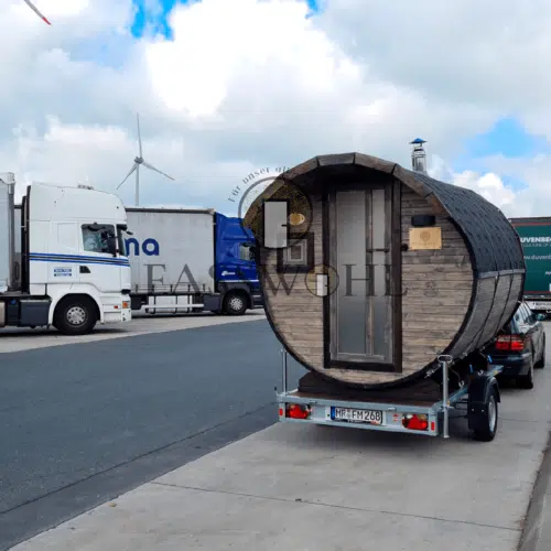 Eine Holz Fasssauna auf dem Rastplatz mit LKWs im Hintergrund