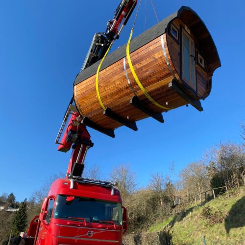 Das Saunafass wird mit einem Kran über einen LKW gehoben